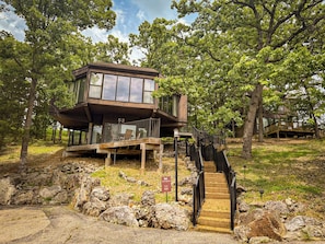 This modern elevated home offers a unique "treetop" living experience, blending seamlessly with the surrounding lush natural landscape. Multiple large windows allow for abundant natural light and scenic views, making this a bright and inviting retreat.