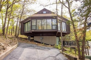 This modern elevated home offers a unique "treetop" living experience, blending seamlessly with the surrounding lush natural landscape. Multiple large windows allow for abundant natural light and scenic views, making this a bright and inviting retreat.