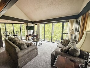  Unit 53’s living room offers comfort and style with a wooded view just outside your window.