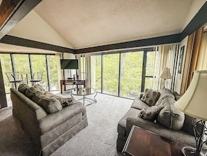 Unit 53’s living room offers comfort and style with a wooded view just outside your window.