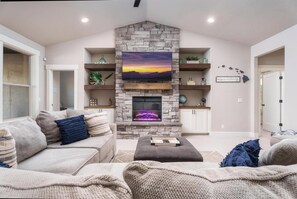 Living Room with large sectional,  electric fireplace and game cabinet. 