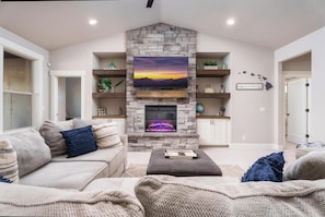 Living Room with large sectional, electric fireplace and game cabinet.