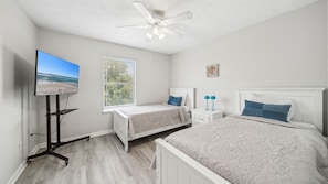 This twin bedroom offers a clean and airy feel with soft bedding, crisp white furniture, and calming blue accents. Natural light pours through the window, creating a peaceful and welcoming space. It’s the perfect room for kids or guests to unwind in comfo