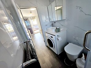 Fully functioning bathroom with toilet, shower, hand basin, mirror vanity and washing machine.