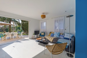 Salon spacieux avec TV, clim, jeux, ouvert sur terrasse et jardin au calme.