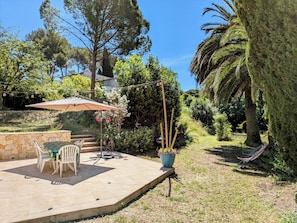Jardin 1500 m² avec terrasse, coin repas, transats, barbecue et nature calme.