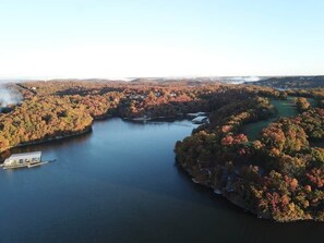 This expansive aerial view showcases the stunning Lake of the Ozarks, surrounded by vibrant fall foliage, offering a truly picturesque setting. The property boasts multiple boat docks, providing convenient access to the water for all your aquatic adventures.