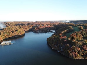 This expansive aerial view showcases the stunning Lake of the Ozarks, surrounded by vibrant fall foliage, offering a truly picturesque setting. The property boasts multiple boat docks, providing convenient access to the water for all your aquatic adventures.
