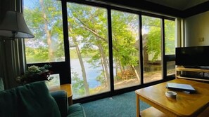 A cheerful living room with a breathtaking lake view, where sunshine, nature, and cozy comforts come together to create a joyful retreat.