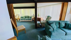 Cozy living room! The mix of seating arrangements creates a welcoming and relaxed vibe. The large windows let in plenty of natural light, making the space feel open and airy.