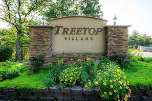This inviting entrance to Treetop Village welcomes you with a beautifully landscaped monument sign, featuring charming stone pillars and lush greenery. The vibrant flowers and well-maintained surroundings immediately convey a sense of community and curb appeal, setting a pleasant tone for residents and visitors alike.