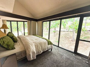 "Wake up surrounded by nature! This serene bedroom features expansive windows, offering peaceful views and abundant natural light."