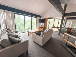 "Relax and unwind in our spacious living room, where large windows bring the beauty of the outdoors inside. Plenty of room for everyone to gather!"