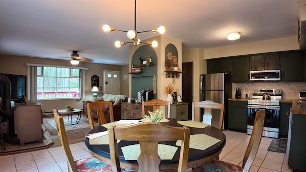 Open-concept main level featuring a fully remodeled kitchen with coffee bar, inviting dining area, and cozy living room with comfortable seating and warm ambient lighting—perfect for gathering and unwinding together.