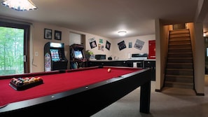 Fun-filled basement game room featuring a pool table, bar area, and retro arcade games—just steps from a cozy movie lounge with a spacious sectional for the ultimate entertainment experience.