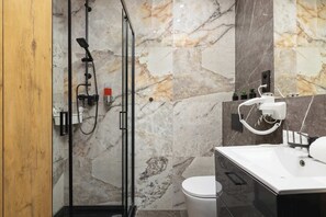 Modern bathroom with glass shower, beige tiles, and toilet/sink.