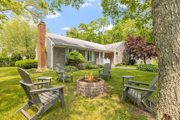 Gather 'round the fire pit under the stars—this cozy circle of Adirondack chairs is made for laughter, stories, and s'mores.