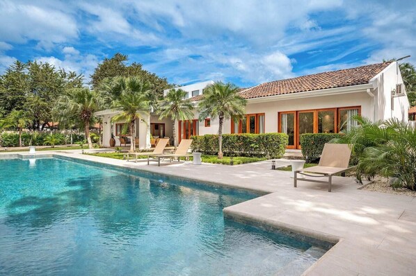 Oversized private pool surrounded by lush gardens and palm trees.