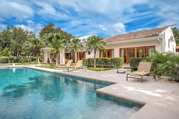 Oversized private pool surrounded by lush gardens and palm trees.
