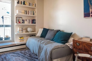 2nd bedroom with single bed, chair and booking shelves