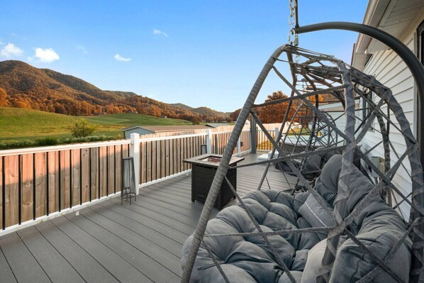 The back deck includes two comfortable egg chairs, a propane firepit, a hot tub and peaceful mountain views.
