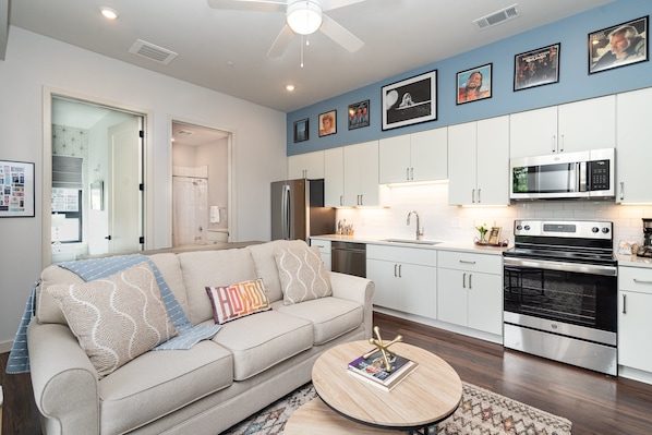 Open floor, fully equipped kitchen featuring stainless steel appliances and a dining table offering breakfast bar seating for 3 guests.