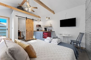 Open guest suite with vaulted ceiling, bed, and full amenities.