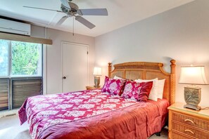 NAP-B43 The master bedroom features a bold tropical bedspread, natural light streaming through the lanai doors, and a peaceful vacation ambiance.