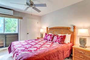 NAP-B43 The master bedroom features a bold tropical bedspread, natural light streaming through the lanai doors, and a peaceful vacation ambiance.