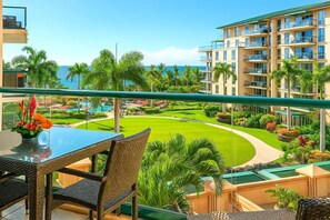 HKH-423 Scenic lanai dining with lush resort landscaping, mountain-lined horizon, and distant ocean sparkle.