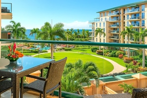 HKH-423 Scenic lanai dining with lush resort landscaping, mountain-lined horizon, and distant ocean sparkle.