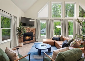 Relax in a warm, inviting living room filled with natural light streaming through expansive windows—perfect for unwinding while soaking in the beautiful surroundings.