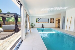 Espace piscine intérieur lumineux, avec un bel aperçu sur le jacuzzi et la terrasse extérieure.