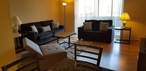 The living room comes furnished with essential pieces, including a comfortable sofa, a coffee table, and a TV stand, providing immediate comfort upon move-in.