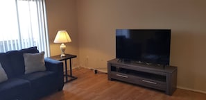 The living room comes furnished with essential pieces, including a comfortable sofa, a coffee table, and a TV stand, providing immediate comfort upon move-in.