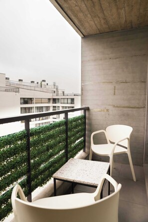 Cozy balcony with seating and privacy screen, perfect for enjoying a morning coffee with a city view.