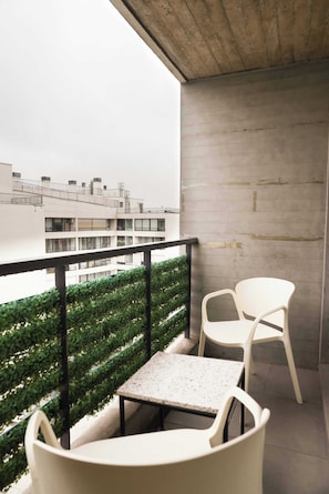 Cozy balcony with seating and privacy screen, perfect for enjoying a morning coffee with a city view.
