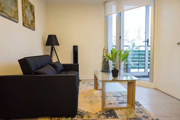 Relax in this stylish living room with a comfy sofa, chic decor, and a view of the balcony. Perfect for unwinding after exploring the city.