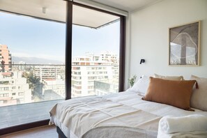 Relax in this bright bedroom with stunning city views and modern decor, perfect for a peaceful getaway.