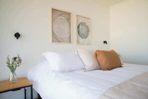 Relax in this serene bedroom with cozy linens and stylish decor, perfect for unwinding after a day of exploring.