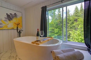 Salle de bain privé avec un bain autoportant avec vue sur la forêt