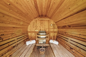 Interior of the cedar-lined sauna with benches and traditional stove—luxury in a natural setting.