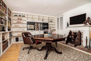 Our living / dining room, equipped with a library, smart TV, mini-fridge, toaster oven / air fryer, ice machine, Keurig coffee maker, sink, and a hidden pool / poker table.