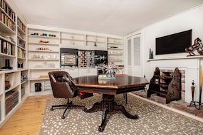 Our living / dining room, equipped with a library, smart TV, mini-fridge, toaster oven / air fryer, ice machine, Keurig coffee maker, sink, and a hidden pool / poker table.