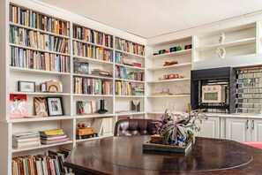 Our living / dining room, equipped with a library, smart TV, mini-fridge, toaster oven / air fryer, ice machine, Keurig coffee maker, sink, and a hidden pool / poker table.