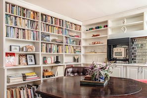 Our living / dining room, equipped with a library, smart TV, mini-fridge, toaster oven / air fryer, ice machine, Keurig coffee maker, sink, and a hidden pool / poker table.