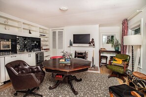 Our living / dining room, equipped with a library, smart TV, mini-fridge, toaster oven / air fryer, ice machine, Keurig coffee maker, sink, and a hidden pool / poker table.
