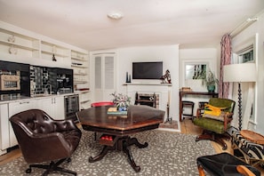 Our living / dining room, equipped with a library, smart TV, mini-fridge, toaster oven / air fryer, ice machine, Keurig coffee maker, sink, and a hidden pool / poker table.