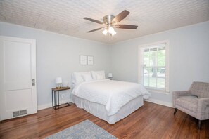 Bedroom with queen bed, serene with blue hues. Chair in corner, large closet. Windows on two sides.