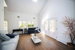 Sunny, spacious living room with cozy seating and high ceilings.
